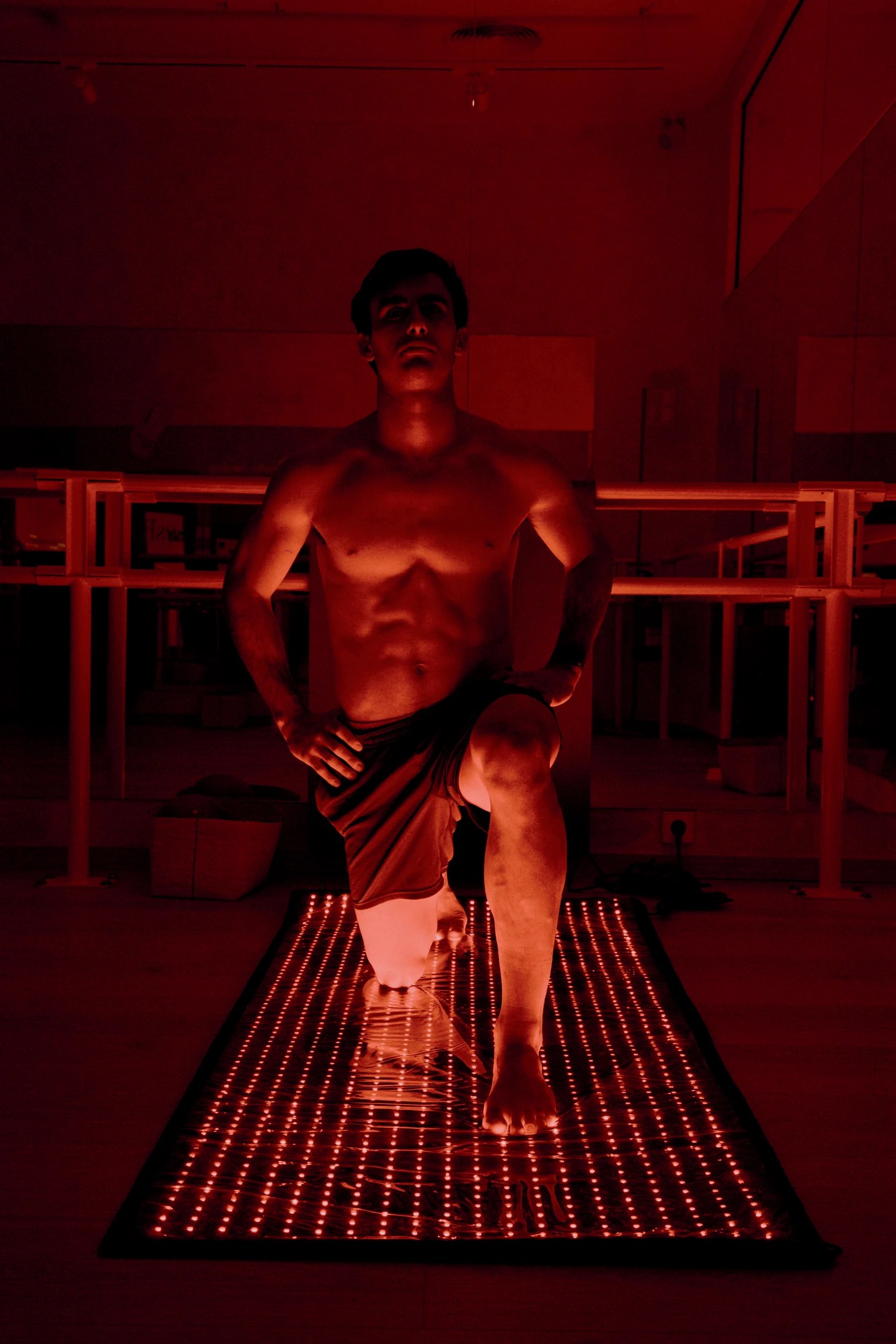 Persona con una rodilla apoyada sobre una superficie de luces LED rojas.